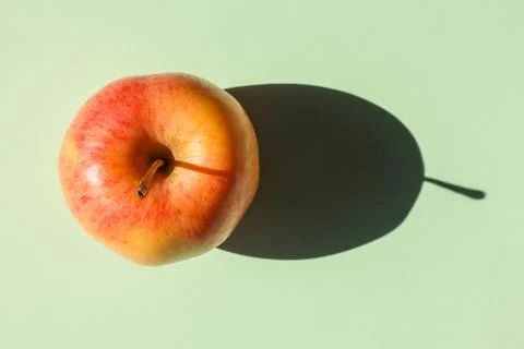 An Apple with a hard shadow on a plain background. the view from the top. blank 库存照片