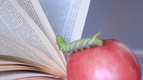 Apple has a worm to climb on top and book background, 스톡 동영상 107378475