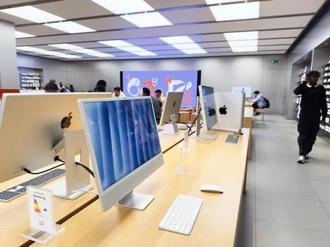 Apple iMac computer workstations in a tech store with customers and displays Stock Photos
