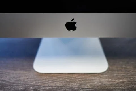 Apple iMac modern computer. Apple logo on monitor, workplace in office. New h Stock Photos