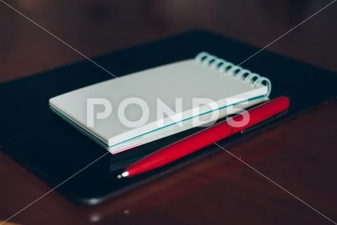 Apple iPad, pen and notebook on wooden desk. Stock Photos