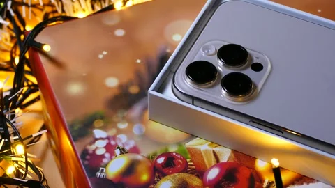 Apple iPhone 16 Pro Max Desert Titanium on Christmas background Stock Footage 323314922