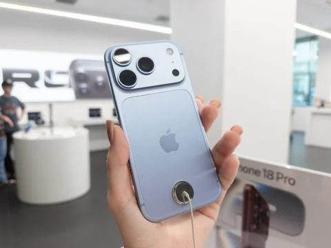 Apple iPhone 18 Pro in Glacier color held in a hand at a retail store, showing Stock Photos