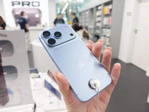 Apple iPhone 18 Pro in Glacier color held in a hand at a retail store, showing Stock Photos