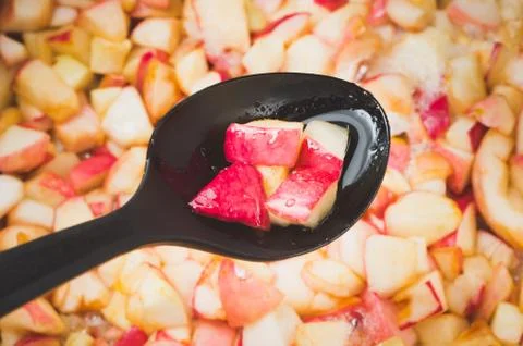 Apple jam making in process, focus on the apple pieces cupping up in the blac Foto stock