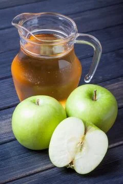 Apple juice in pitcher on table, vertical still life Stock Photos
