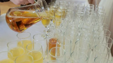 Apple juice is poured into glasses. Buffet table with juice, champagne and fruit Stock Footage 253325224