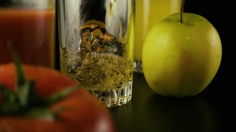 Apple juice is poured into one of the three glasses on the table. Slow mo Stock Footage 74920577