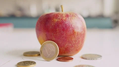 An apple lies on the kitchen table. Next to it are individual euro coins. Stock Footage 333010131