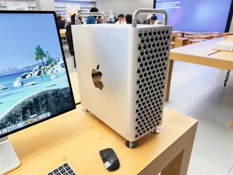 Apple Mac Pro computer tower beside a sleek monitor in a tech showroom settin Stock Photos