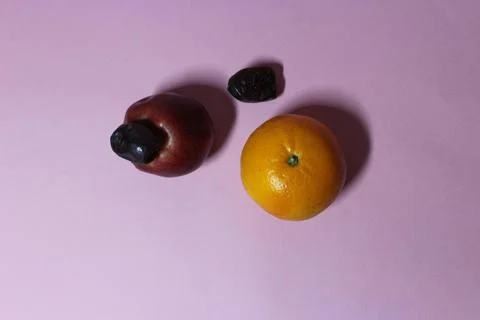 Apple orange and date fruit on a pink background Stock Photos