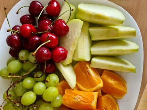Apple, Orange, grape, and Cherry fruits on plate. Nutrition fruits for health Fotos de archivo