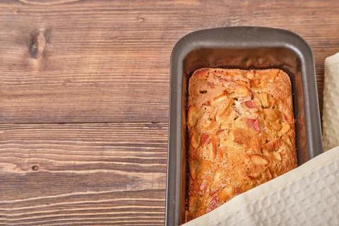 Apple pie in a baking tray on a brown wooden table. Apple charlotte. Homemade Stock Photos