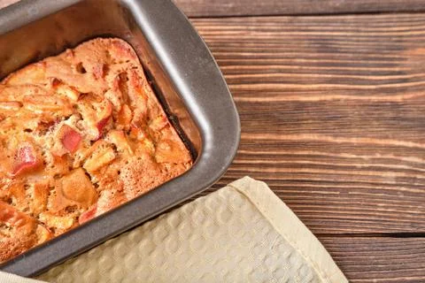 Apple pie in a baking tray on a brown wooden table. Apple charlotte. Homemade Stock Photos
