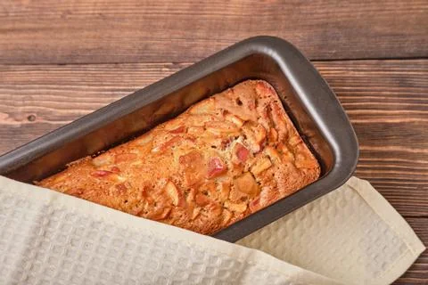 Apple pie in a baking tray on a brown wooden table. Apple charlotte. Homemade Stock Photos