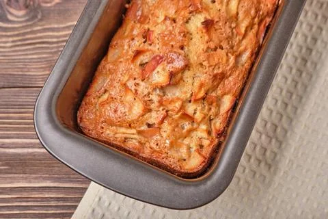 Apple pie in a baking tray on a brown wooden table. Apple charlotte. Homemade Stock Photos