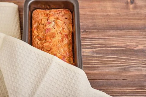 Apple pie in a baking tray on a brown wooden table. Apple charlotte. Homemade Stock Photos