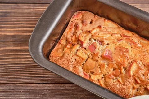 Apple pie in a baking tray on a brown wooden table. Apple charlotte. Homemade Stock Photos