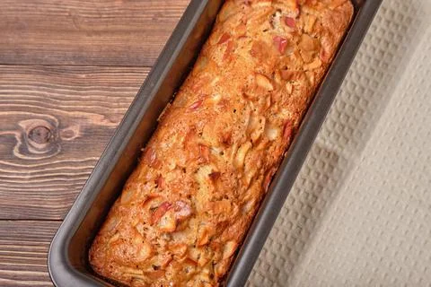 Apple pie in a baking tray on a brown wooden table. Apple charlotte. Homemade Stock Photos