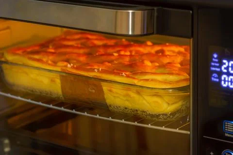 Apple pie in an electric oven with backlight Stock Photos