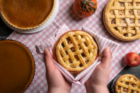 Apple pie held in hands over a table with many pies. Sweet pies baking. Above Stock Photos