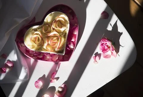 Apple pie in the shape of a heart stands on a white chair,the rays of the light Stock Photos