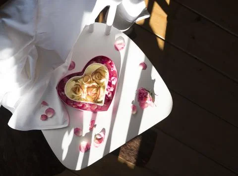 Apple pie in the shape of a heart stands on a white chair,the rays of the light Stock Photos