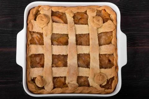 Apple pie in a square ceramic baking sheet on a dark wooden background Stock Photos