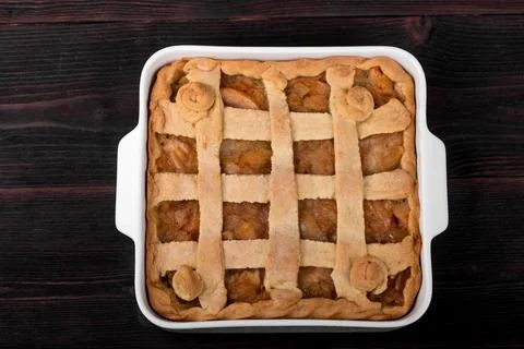 Apple pie in a square ceramic baking sheet on a dark wooden background Stock Photos