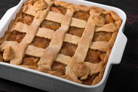 Apple pie in a square ceramic baking sheet on a dark wooden background Stock Photos