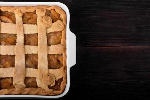Apple pie in a square ceramic baking sheet on a dark wooden background Stock Photos