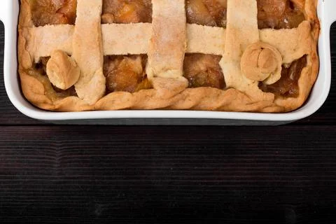 Apple pie in a square ceramic baking sheet on a dark wooden background Stock Photos