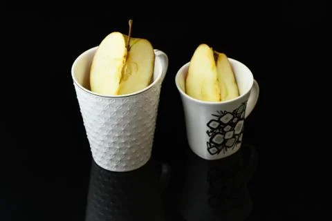 Apple pieces on isolated black background in white glass Stock Photos