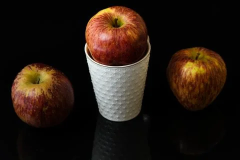 Apple pieces on isolated black background in white glass Stock Photos