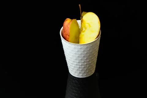 Apple pieces on isolated black background in white glass Stock Photos