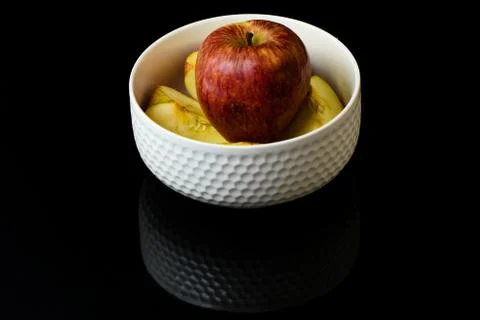 Apple pieces on isolated black background in white cup Stock-Fotos