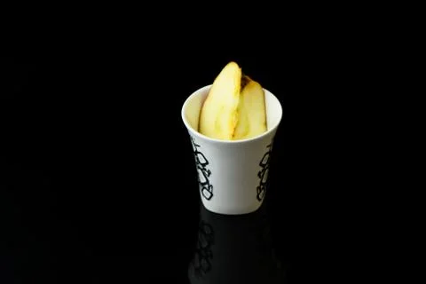 Apple pieces on isolated black background in white cup Stock Photos