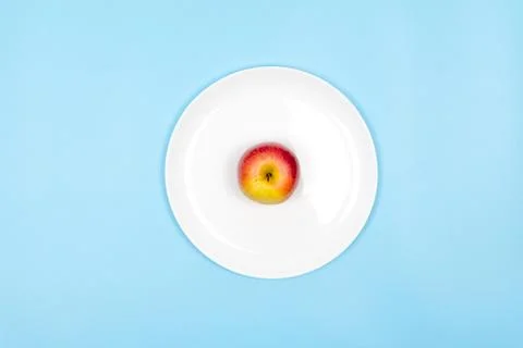 An apple on a plate. Blue background. Foto stock