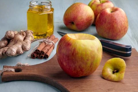 An apple prepared for baking in the oven surrounded by ingredients with honey Foto stock
