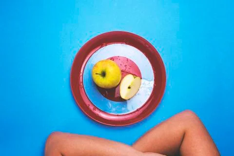 Apple on a red plate on a colored background. Stock Photos