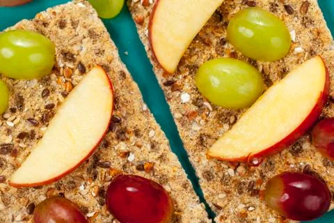 Apple segments and grapes on multigrain crispbread Stock Photos
