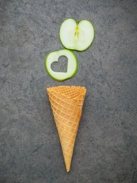 Apple slice in waffle cones and heart shape of apple setup on dark stone back Stock Photos