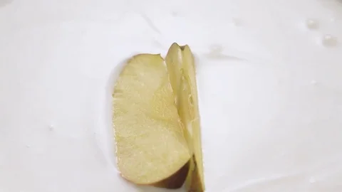 Apple slices falling into yogurt with splashes, slow motion. Stock Footage 84949917