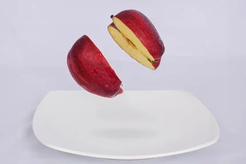 An apple split in the air on a white plate Foto stock