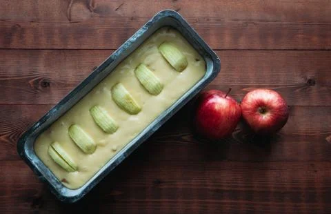 Apple sponge cake before baking on a dark wooden base with apple decorations. Stock Photos