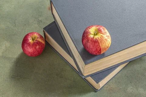 Apple on stack of book on green wood table study. Stock Photos