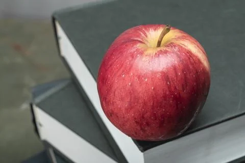 Apple on stack of book on green wood table study. Stock Photos