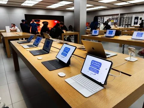 Apple store showroom with multiple iPad Pro laptops and tablets on wooden t.. Stock Photos