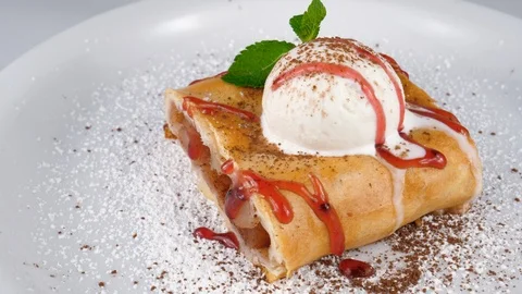 Apple strudel, decorated with ice cream, jam and mint leaf on top, loop Stock Footage 95345397