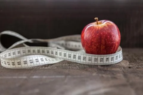 An Apple surrounded by a measuring tape tailor on wood Stock Photos